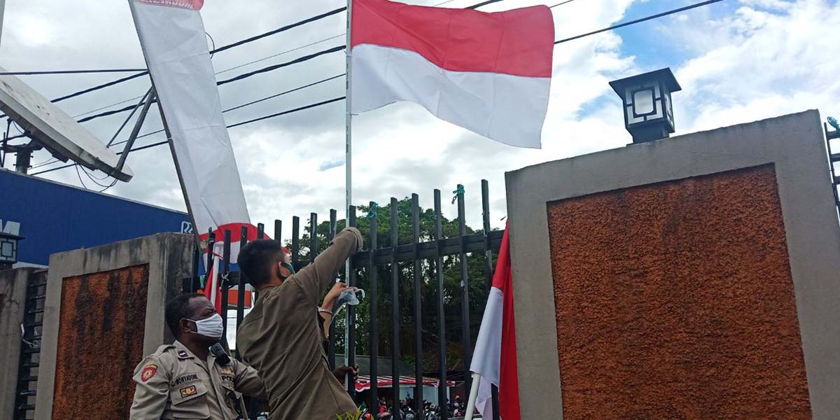 Personel Polres Mimika mendirikan bendera merah putih di pagar Kantor Pelayanan Polres Mimika, Kamis (06/08/2020).
